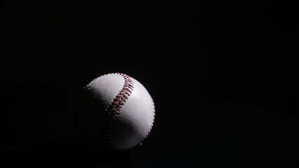 White leather baseball poses on black background.