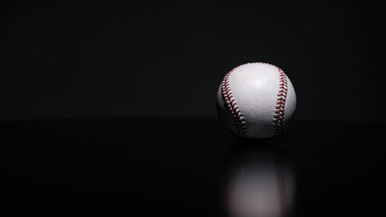 White leather baseball poses on black background.