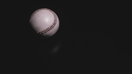 White leather baseball poses on black background.