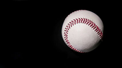 White leather baseball poses on black background.