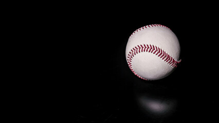 White leather baseball poses on black background.