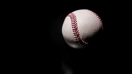 White leather baseball poses on black background.
