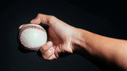 Selective focus of man holding baseball ball isolated on black background.