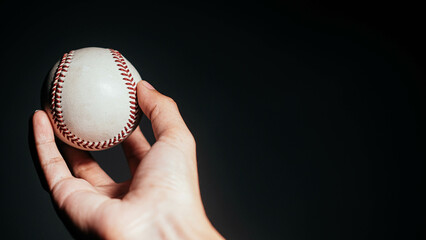 Selective focus of man holding baseball ball isolated on black background.