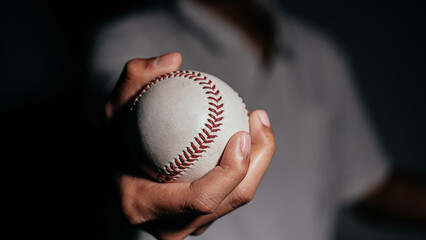 Selective focus of man holding baseball ball isolated on black background.