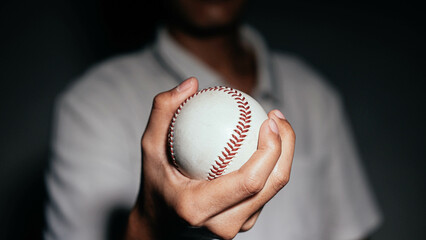 Selective focus of man holding baseball ball isolated on black background.