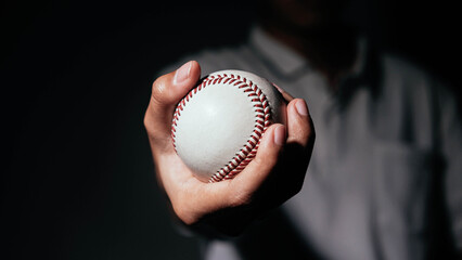 Selective focus of man holding baseball ball isolated on black background.