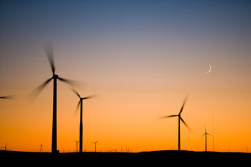 Crescent Moon and wind turbine silhouettes at sunset