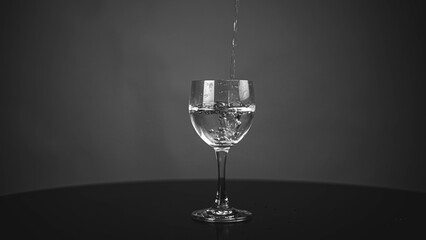 Pour pure drinking water into a glass. a glass with water set on a gray background.