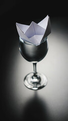 Glass of water with paper origami boat Concept. Paper Boat Floating On Water In Glass On Table.