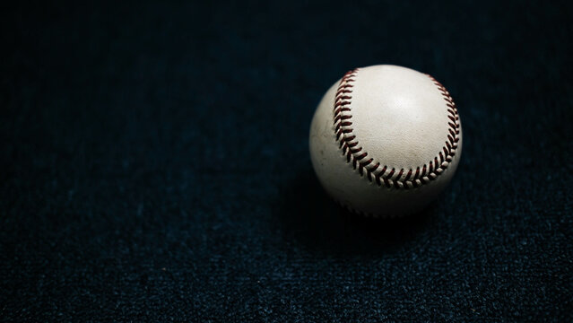 White leather baseball poses on black background.