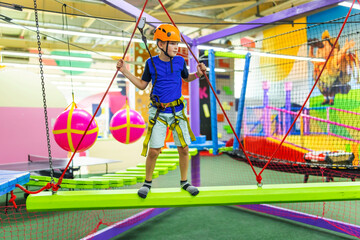 Boy in protective gear holding safety rope and passing obstacle course