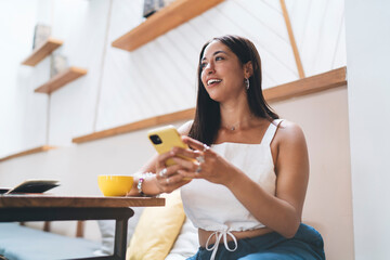 Happy young woman with smartphone in cafe