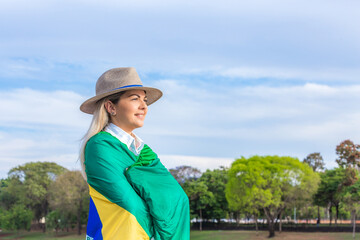 Woman wrapped in a brazilian flag wearing hat and jeans. Agribusiness woman.