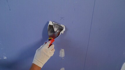 Applying putty to the gypsum plasterboards. Plastering wall with putty-knife, close up image....