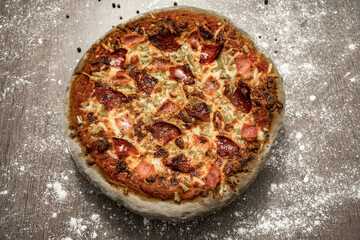 Baked pizza made with gray dough, sweet ham, chorizo, green pepper and cheese. Healthy eating, homemade Italian cuisine. Colored pizza dough.