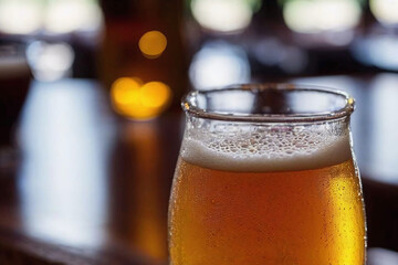 closeup of beer with foam in glass laying on rustic wooden table