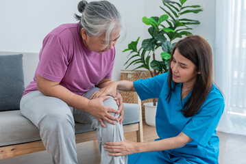 Physical therapist Asian woman, doing leg physiotherapy for elderly woman, to treat osteoarthritis and nerve pain in the leg, to nursing home and health care concept. - obrazy, fototapety, plakaty