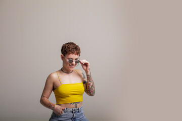 Portrait of a young woman in front of a background with tattoo and sunglasses