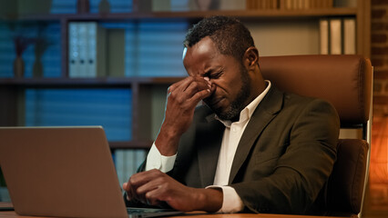 Fototapeta na wymiar Adult african american businessman working on laptop in office unhealthy tired man suffering from headache feels pain pressure fatigue from overwork suffer chronic migraine experiencing health problem