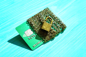 Green credit card wrapped with chains on blue
