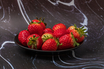 Red strawberries with a green stem are on a beautiful white-black background. Still life with strawberries.