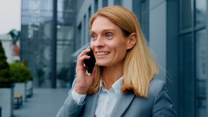 Happy enthusiastic excited woman talking on mobile phone outdoors sharing good experience with friend remotely chatting on smartphone joyful businesswoman speaks on telephone communicating with client