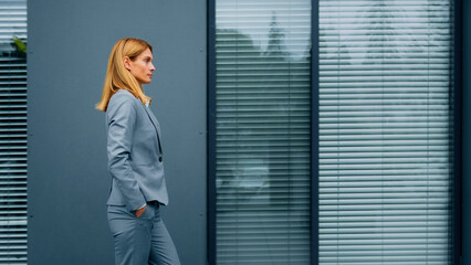 Proud confident stylish woman leader boss professional worker in formal suit walking down street against backdrop of office building successful caucasian serious businesswoman walk outdoors side view - Powered by Adobe