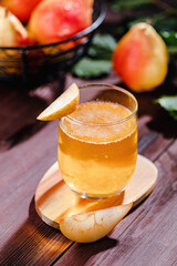Pear drink on a wooden table, with pear slice on the glass