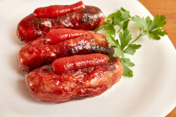 Fried sausages with ketchup on a white plate.