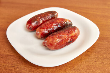 Fried sausages on a white plate.