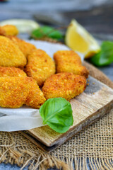 
 Crispy oven baked  chicken Nuggets  with garlic sauce.Breaded chicken fillets  with chilly peppers and fresh basil on wooden rustic background