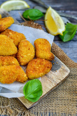 
 Crispy oven baked  chicken Nuggets  with garlic sauce.Breaded chicken fillets  with chilly peppers and fresh basil on wooden rustic background