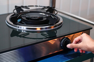 woman's hand turns on a gas hob. protection from children. Gas sanctions concept,  Gas stove with...