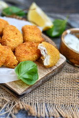 
 Crispy oven baked  chicken Nuggets  with garlic sauce.Breaded chicken fillets  with chilly peppers and fresh basil on wooden rustic background