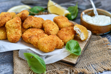 
 Crispy oven baked  chicken Nuggets  with garlic sauce.Breaded chicken fillets  with chilly peppers and fresh basil on wooden rustic background