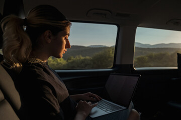 woman working from her laptop while traveling in daylight in a private vehicle,private transportation and daylight