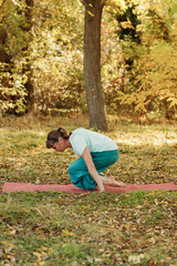 An elderly woman practices yoga in the autumn forest