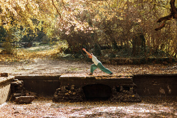An elderly woman practices yoga in the autumn forest