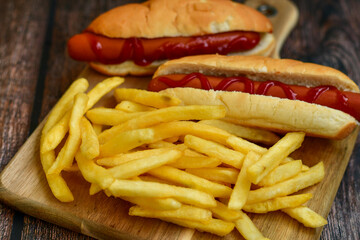 Tasty   Hot dogs and  deep fried french fries  on paper on wooden background