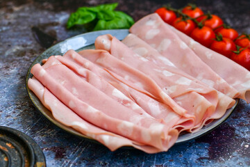 Slices Of  Traditional Italian antipasti mortadella Bolognese  on a wooden  cutting board.