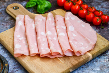 Slices Of Traditional Italian antipasti mortadella Bolognese on a wooden cutting board.