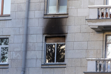 Windows of a multi-storey brick house after a fire. The wall of the house is stained with soot after the fire. Soot on the wall of the house after a fire by negligence.