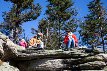 Family on the mountain top, happy couple parents with child on the rock on vacation