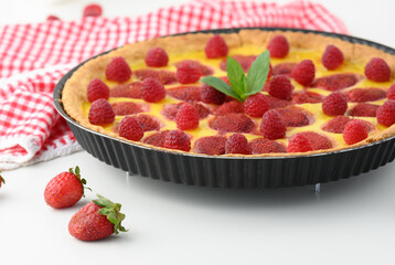 Round quiche with red strawberries and raspberries on a white table, top view
