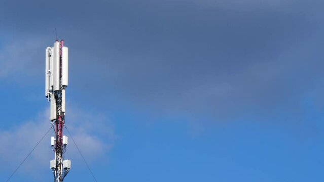 Cell site antenna on a white clouds and blue sky background. Cell tower with mobile Telecommunications equipment. Cellular tower base station with electronic communications equipment. Place for text