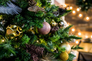 A shiny golden ball on a branch.Christmas tree decorations. New Year's decorations in pink and golden tones. Congratulations on winter holidays. Preparation for the celebration. Postcard.