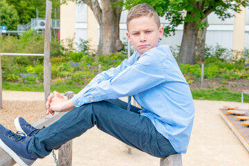boy sitting on a playground with blue skirt an tie frontal