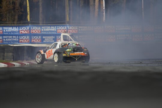 11-05-2022 Riga, Latvia A Car Is Drifting On A Track With Smoke Coming Out Of It, A Car That Is Driving Around A Corner.