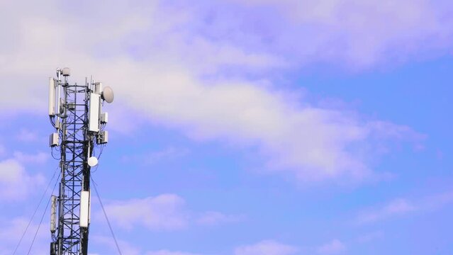 Cell site antenna on a blue sky and white clouds background. Cellular tower base station with electronic communications equipment. Cell tower with mobile Telecommunications equipment. Place for text